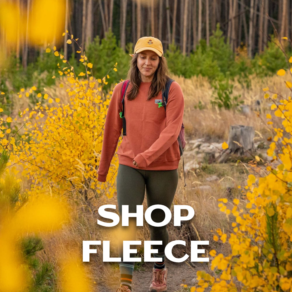 Person walking on a trail in an orange fleece.